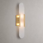 Frosted vertical wall sconce with warm brass accents and glowing light.
