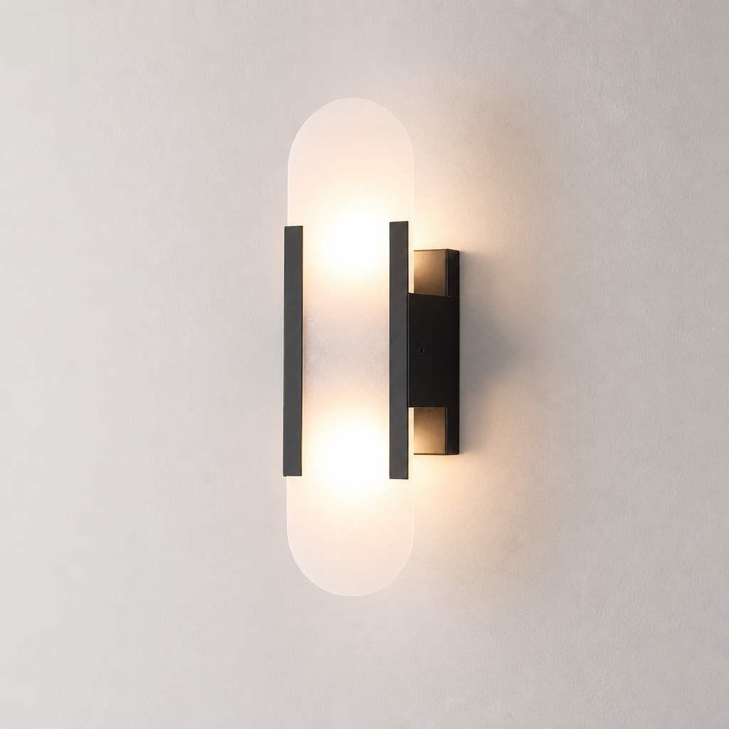 Warm glowing black wall sconce with frosted rounded vertical diffuser on a neutral wall.