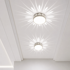 Two round flush ceiling lights with patterned rims casting floral rays on a white ceiling.