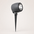 Black cylindrical garden spotlight with silver reflector and ground spike on a light background.