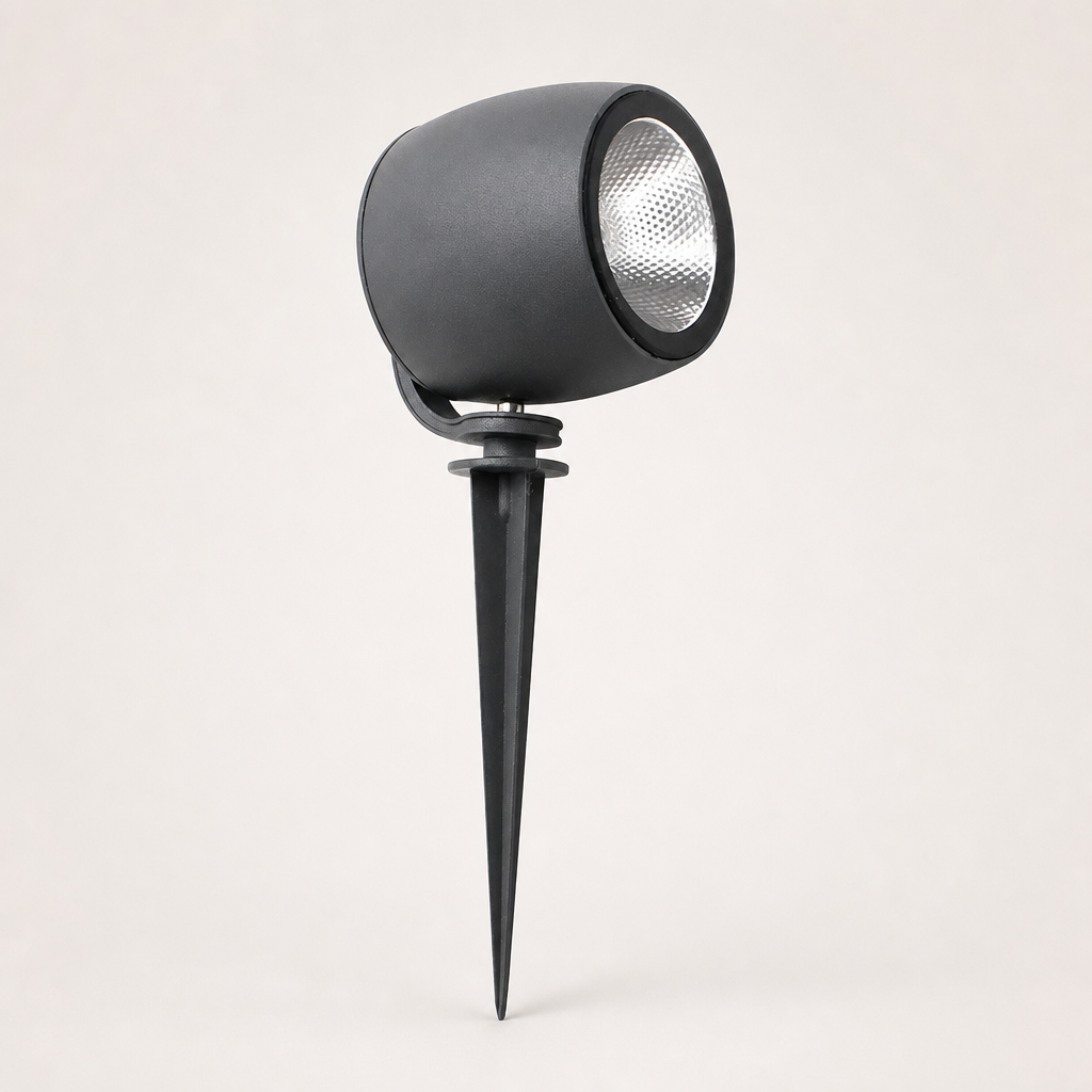 Black cylindrical garden spotlight with silver reflector and ground spike on a light background.