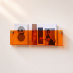 Orange translucent wall shelf holding magazines on a light wall.