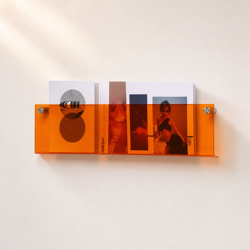 Orange translucent wall shelf holding magazines on a light wall.