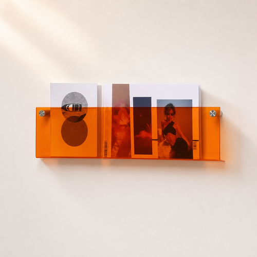 Orange translucent wall shelf holding magazines on a light wall.