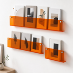Translucent orange acrylic wall shelves display books and magazines on a white wall.