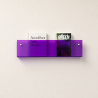 Translucent purple wall-mounted acrylic shelf holding two books on a light wall.