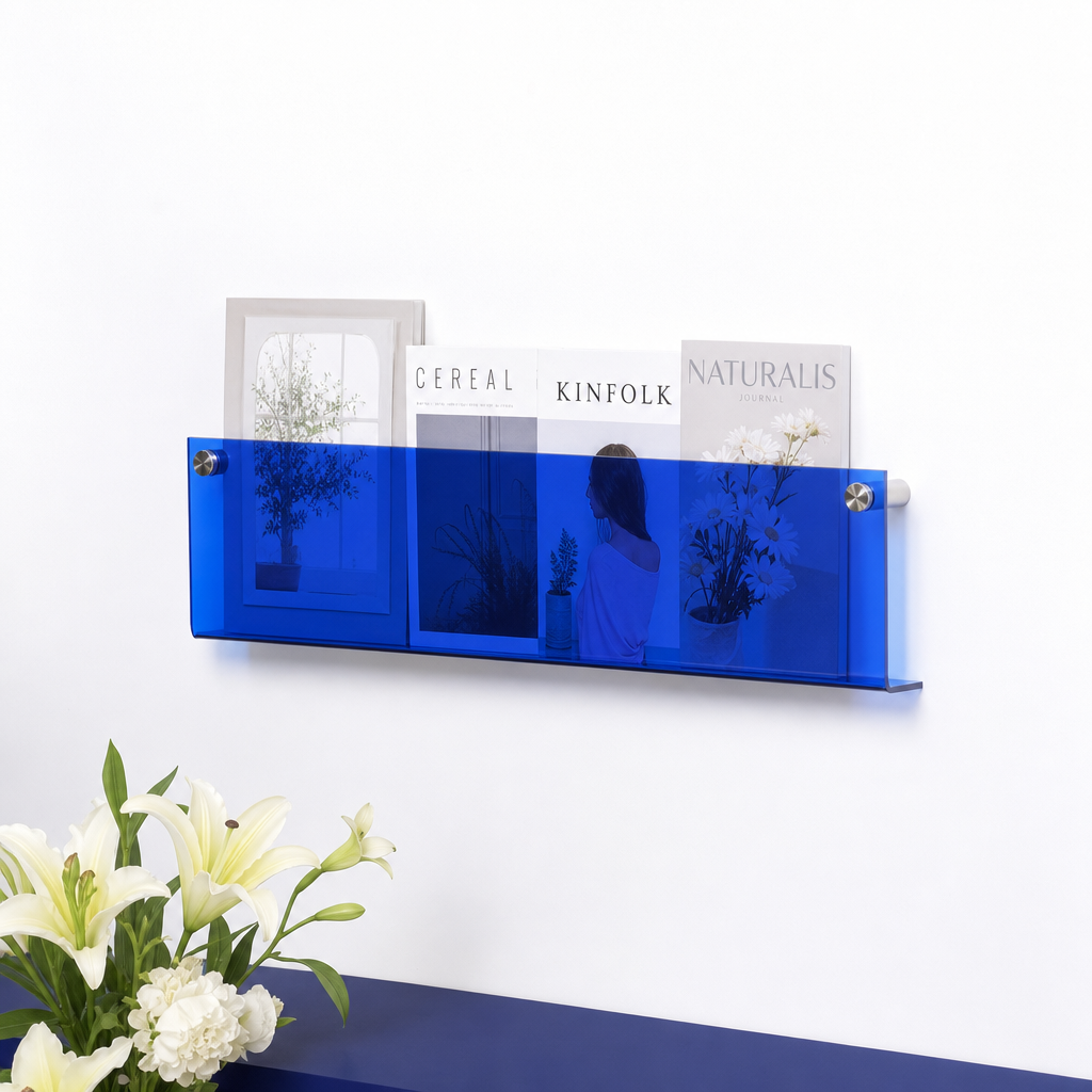 Blue wall-mounted acrylic magazine rack holding assorted magazines with flowers below.
