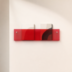 Translucent red wall-mounted magazine shelf holding two books on a pale wall.