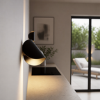 Black wall-mounted spotlight with warm glow above a sleek kitchen counter.