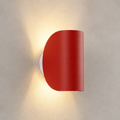 Red half-cylinder wall sconce on a textured pale wall casting a warm glow.