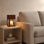 Wooden cube lantern with a glowing candle sits on a side table beside a beige sofa.