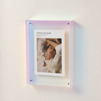 Iridescent acrylic wall frame holding a white photo print with portrait and title text.