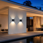 Two black cube wall lights cast geometric beams on a white exterior wall.