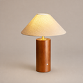 Lit table lamp with beige shade and cylindrical wooden base.