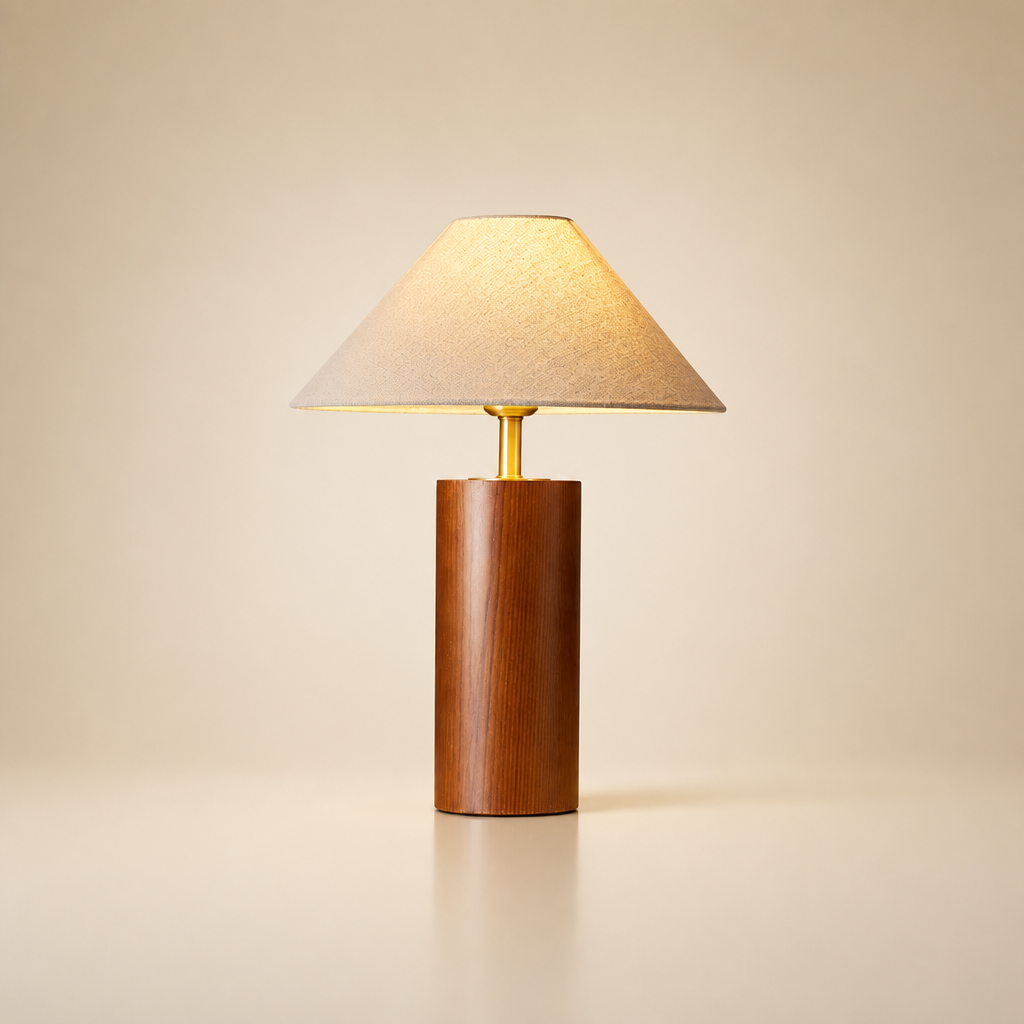 Wooden table lamp with beige fabric shade and brass neck on a plain warm background.