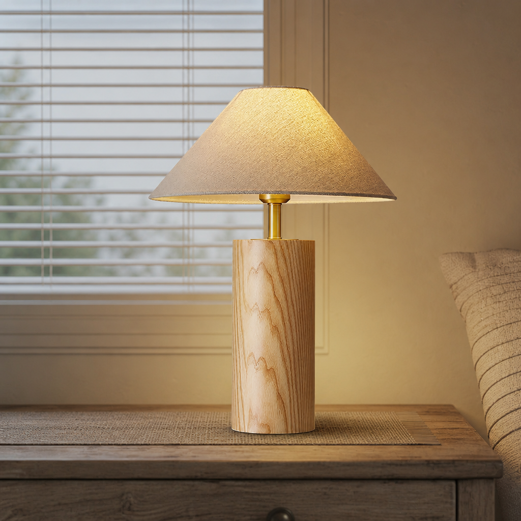 Wooden table lamp with beige shade glowing on a bedside surface.