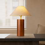 Wooden table lamp with beige fabric shade and gold stem on a modern console.