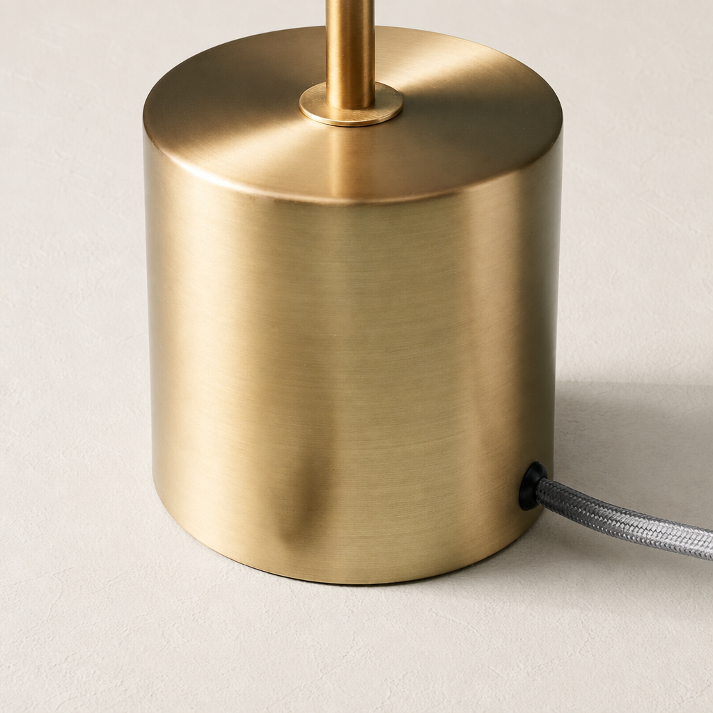Brushed brass cylindrical lamp base with a vertical stem and gray braided cord.