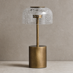 Brass table lamp with a crackled clear glass dome shade on a neutral tabletop.