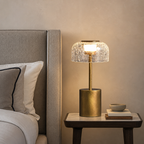 Gold bedside lamp with cracked glass dome shade glowing on a nightstand.