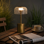 Brass table lamp with a glowing crackled glass dome shade on a wooden table.