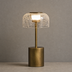 Gold table lamp with cracked glass shade glowing on a neutral tabletop
