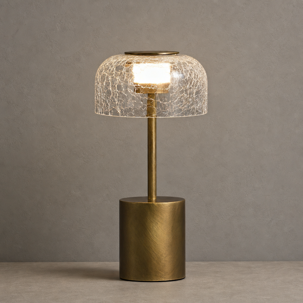 Gold table lamp with cracked glass shade glowing on a neutral tabletop