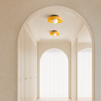 Two yellow flush-mount ceiling lights in a cream arched hallway with soft natural light.