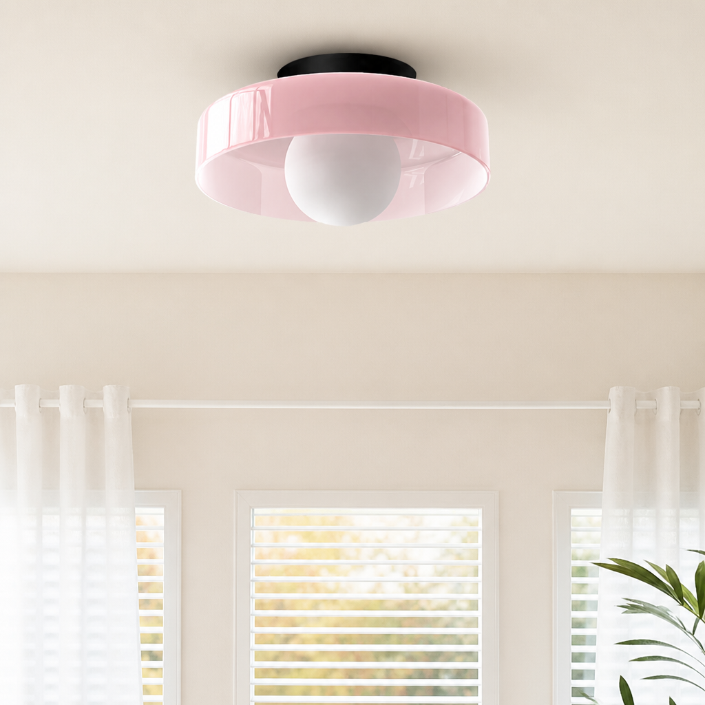Glossy pink ceiling light with a round white bulb in a softly lit room.