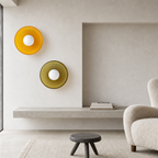 Two circular wall lights, one amber and one olive, displayed in a minimalist living room.