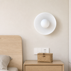 White wall sconce above a woven basket on a light wood bedside table.
