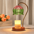 Lit candle warmer lamp with green and pink glass shade on a wooden base.