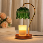 Green ribbed glass candle warmer lamp with gold curved stem, wooden base, and glowing frosted candle.