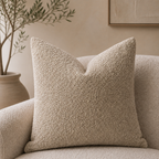 Beige boucle throw pillow on a matching textured armchair in a warm neutral room.