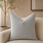 Light gray textured square throw pillow on a cream boucle chair.