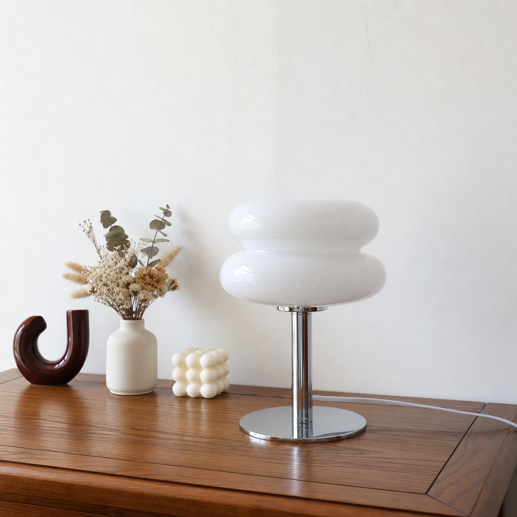 Glossy white double-tier table lamp with chrome stem and round base on a wooden console.
