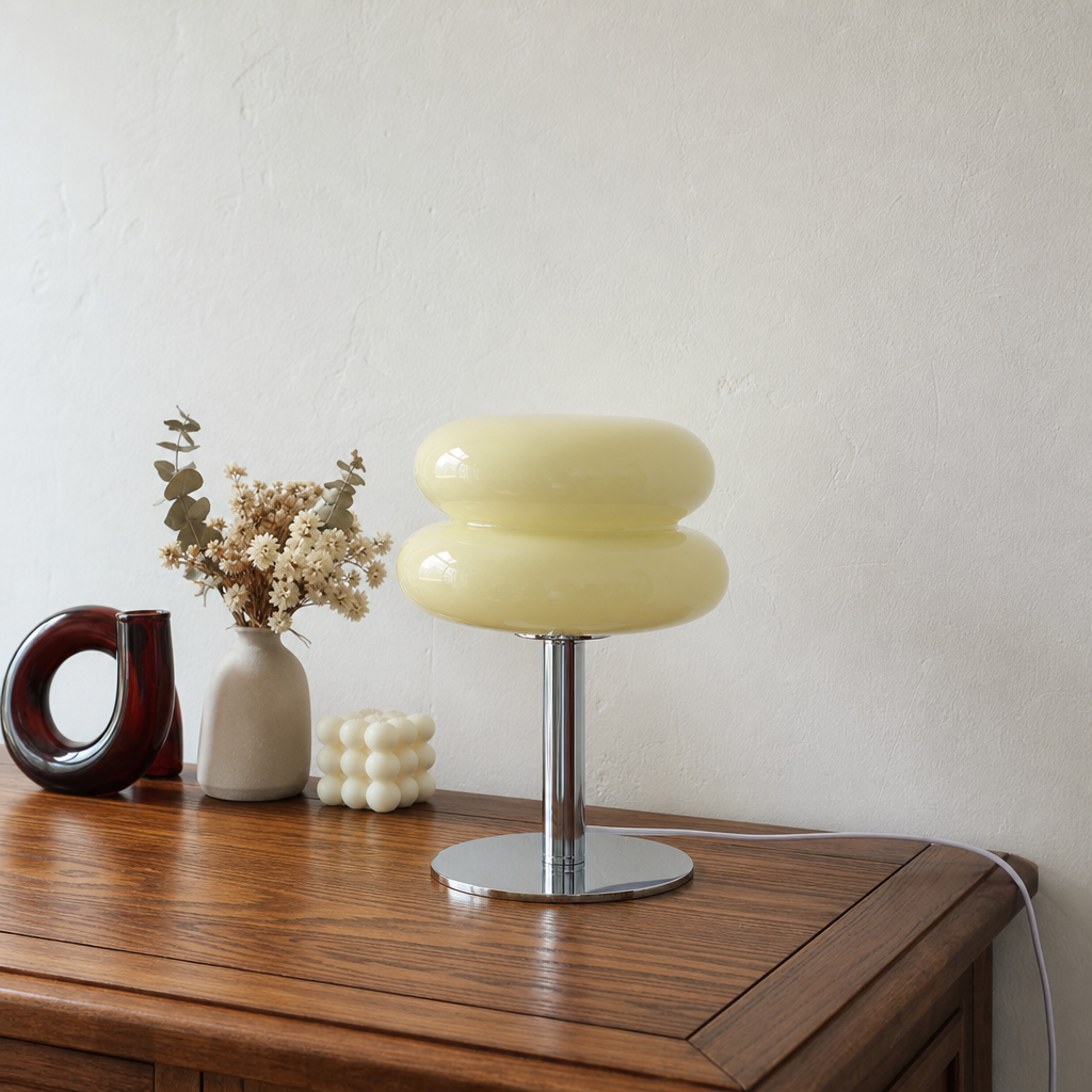 Pale yellow double-dome lamp on a chrome stand atop a wooden console.
