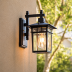 Black outdoor wall lantern with glass panels and a glowing Edison bulb.