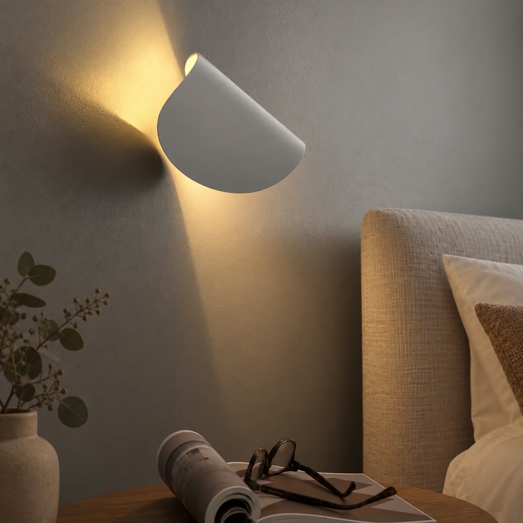 White wall light mounted at an angle beside a bed