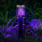 Black outdoor bug zapper lamp glowing purple among garden ferns and rocks.