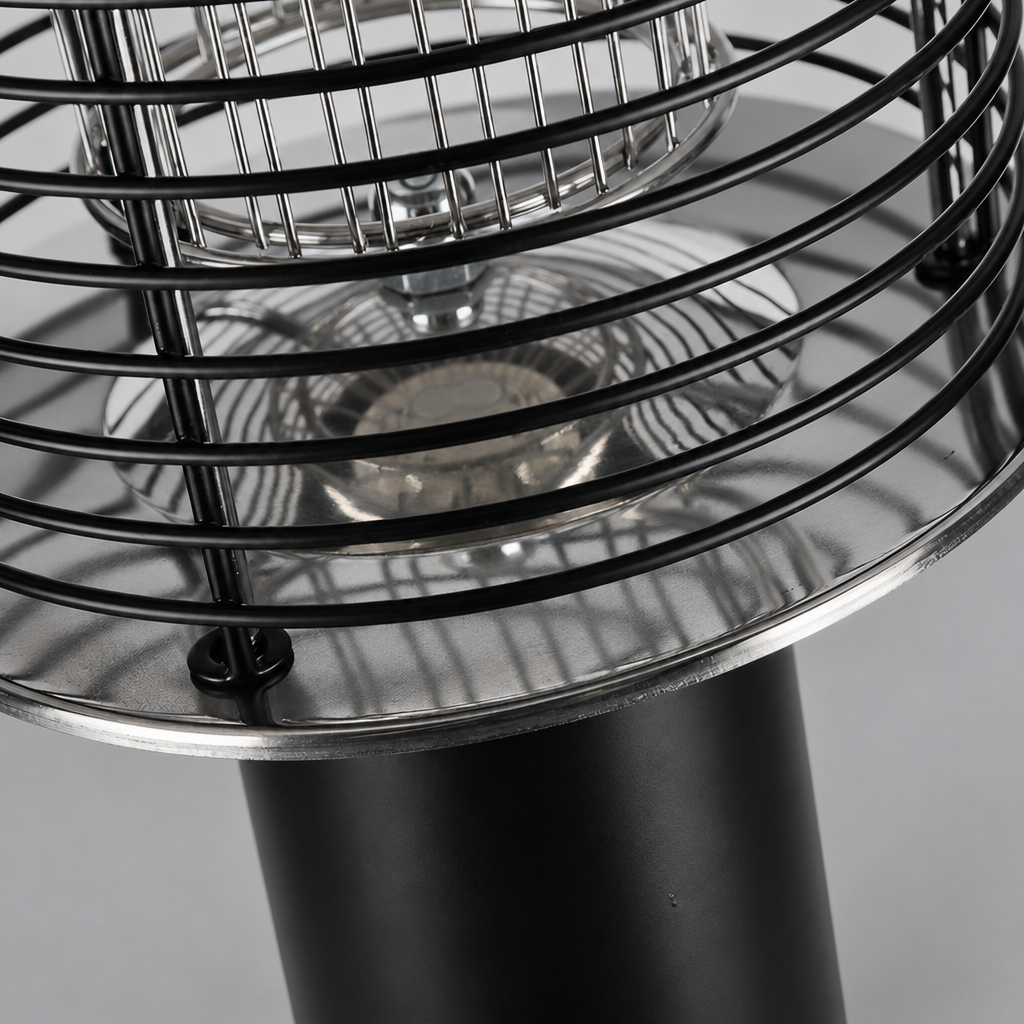 Close-up of a black metal cage heater with reflective chrome dish and cylindrical base.