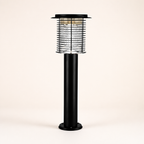 Black outdoor post lantern with a clear caged lamp head and round base.