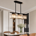 Black three-light rectangular crystal pendant chandelier glowing above a modern dining table.
