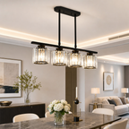 Modern black linear chandelier with four glowing ribbed glass shades over a dining table.