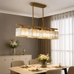 Gold four-light linear chandelier with rectangular crystal shades above a dining table.
