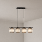 Black four-light linear pendant with glowing ribbed glass shades on a pale corner ceiling.