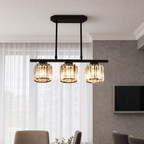Three-light black pendant fixture with amber glass shades hanging above a dining area.