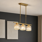Gold three-light linear pendant chandelier with ribbed glass shades hanging from a ceiling.