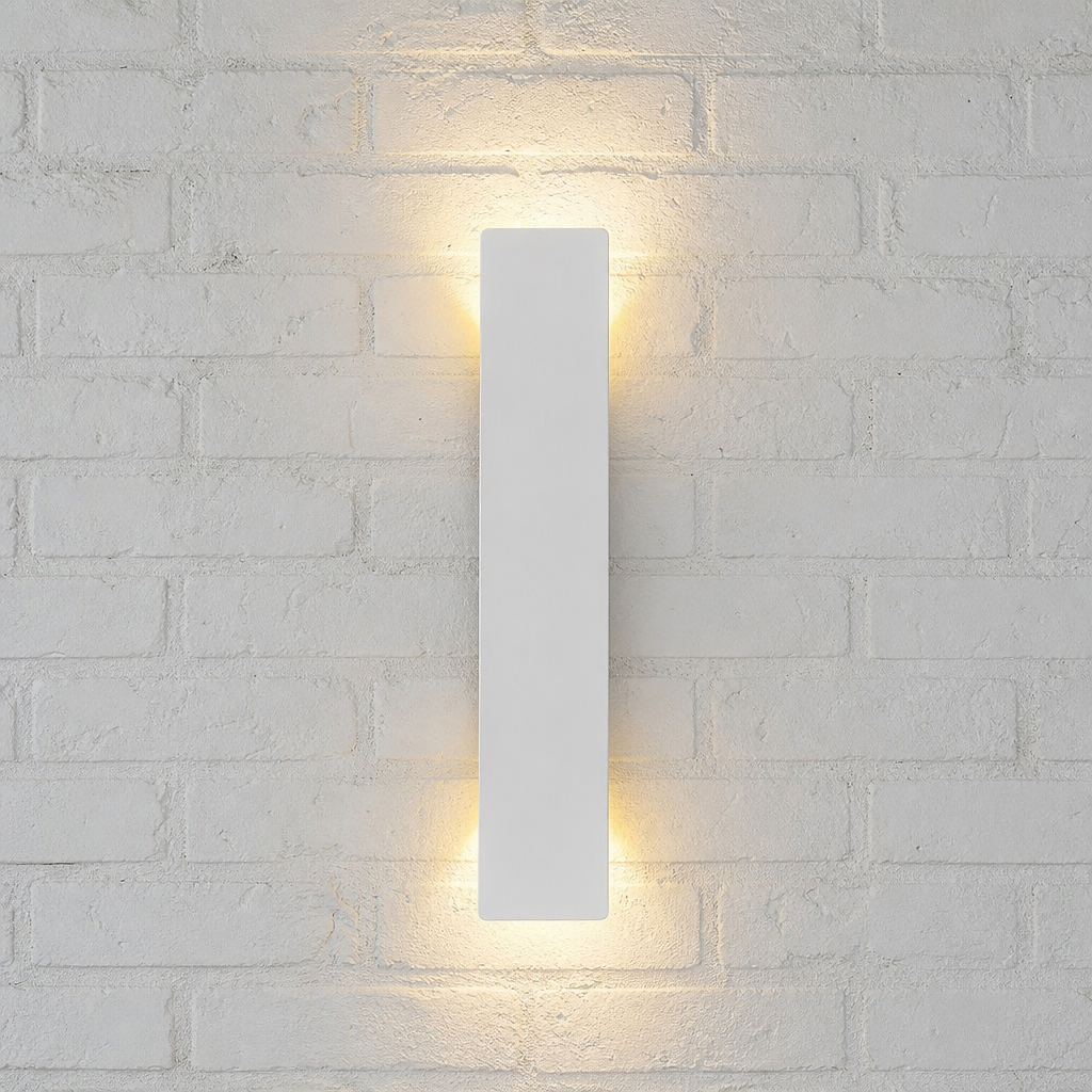 Slim white rectangular wall sconce glowing warmly on a pale textured brick wall.