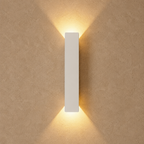 White rectangular wall light casting warm beams on a textured beige wall.
